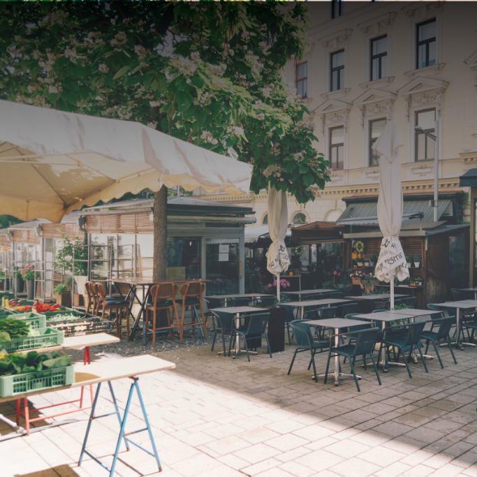Marktstände und Café-Sitzplätze unter Bäumen am Kutschkermarkt in Wien-Währing.