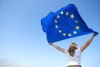 rueckansicht-der-jungen-frau-die-die-flagge-der-europaeischen-union-schwenkt