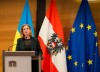 Beate Meinl-Reisinger am Rednerpult, hinter ihr Flaggen von Ukraine, Österreich und EU
