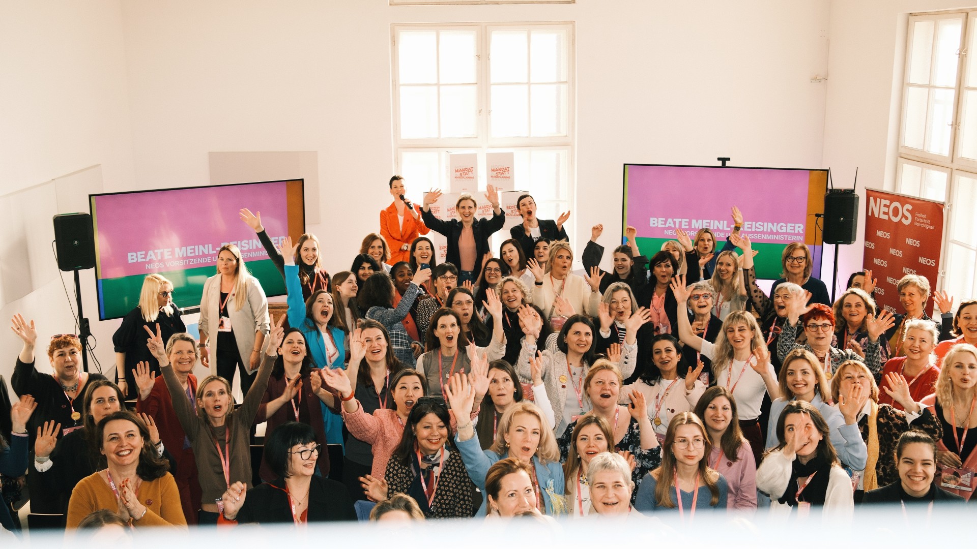 Viele Frauen auf der NEOS-Frauenkonferenz winken in die Kamera