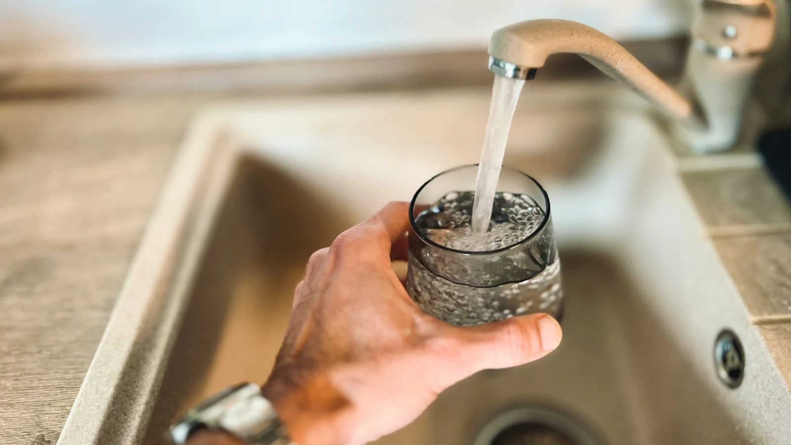 Wasser aus dem Hahn in ein Glas in einer Spüle in Österreich