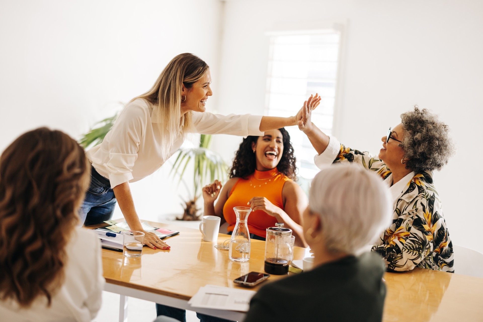 Frauen in einem Konferenzraum, zwei klatschen ab