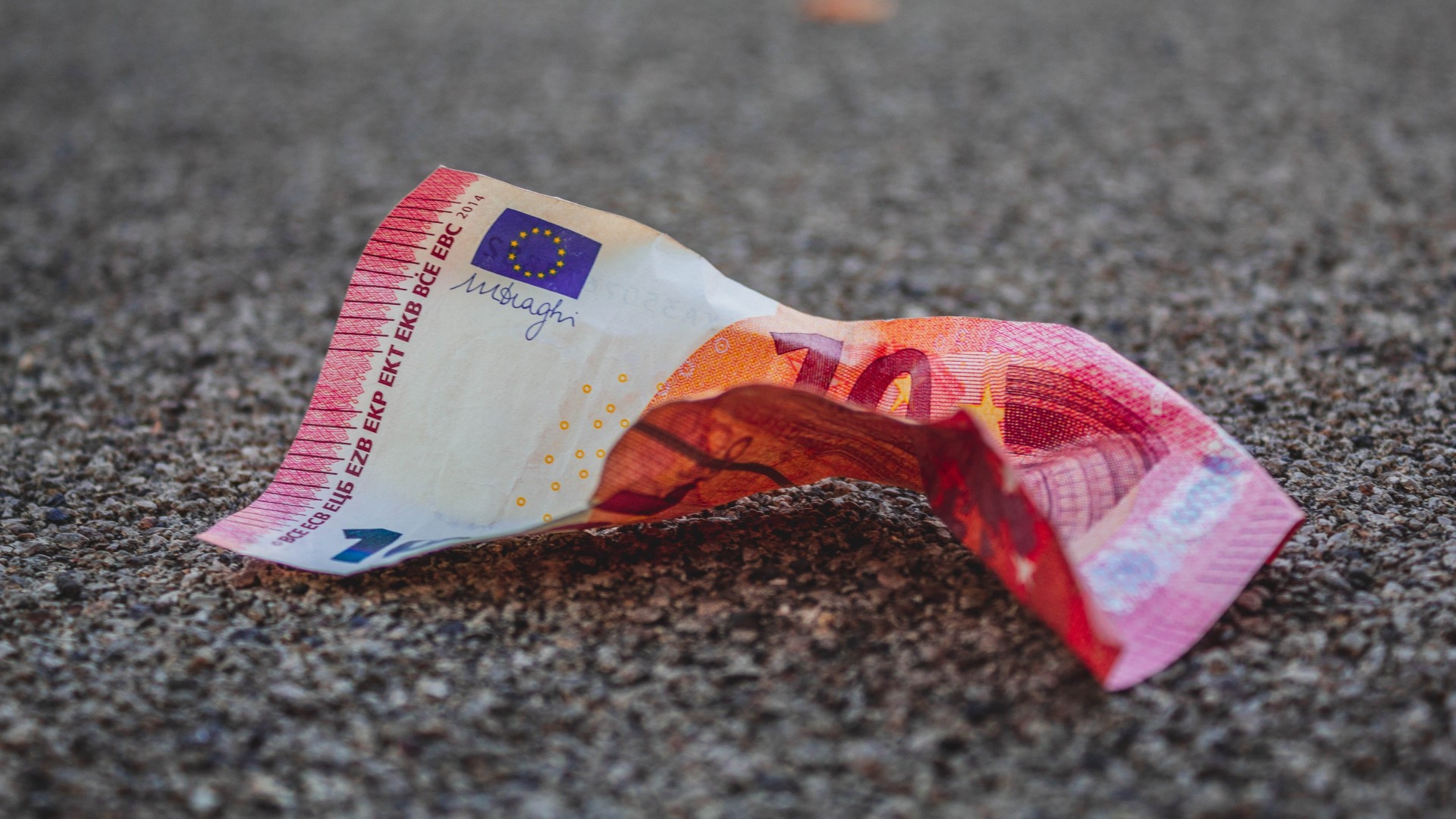 ein zerknitterter 10-Euro-Schein auf Asphalt