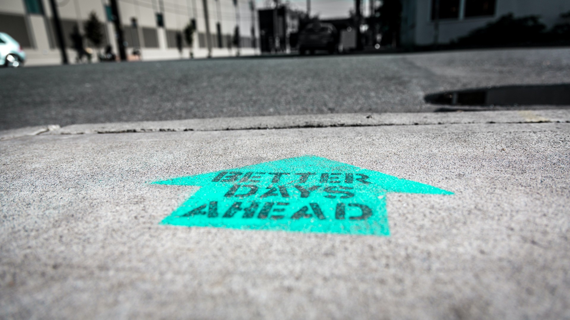Asphalt, darauf ein türkiser Pfeil mit dem Text "Better days ahead"