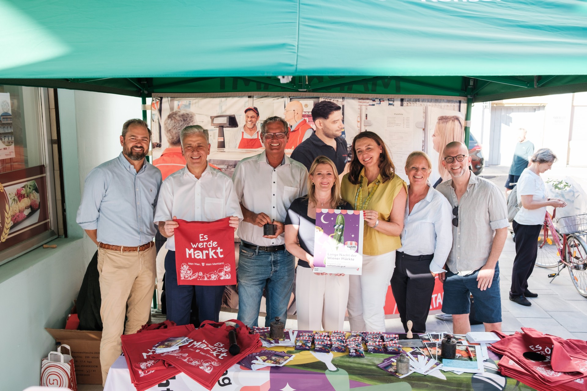 Gruppenfoto mit Bettina Emmerling, Selma Arapovic, Markus Ornig und weiteren Gästen bei einem Marktstand