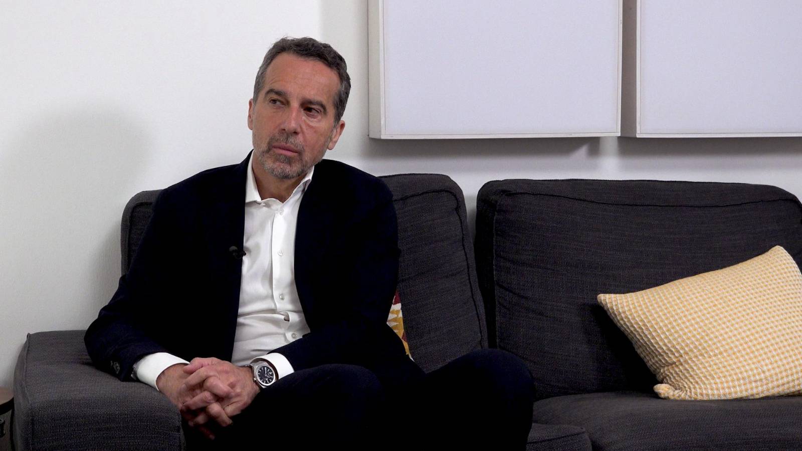 Christian Kern sitzt auf einem Sofa und wartet die frage von Beate im Podcast ab