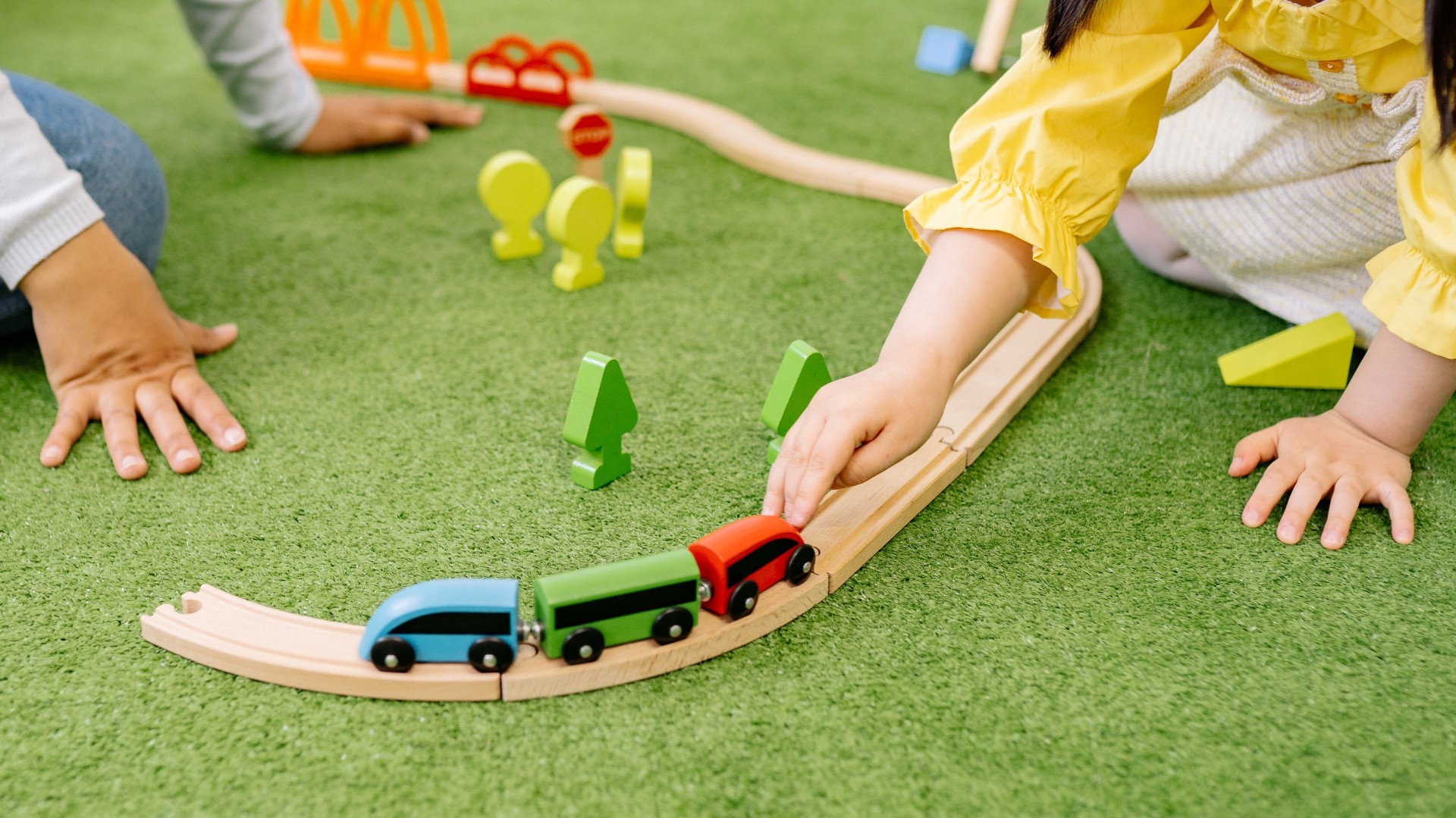 Kinderhände, die mit einer Holz-Eisenbahn spielen